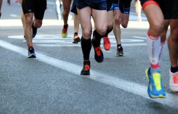 舗装された道路を走る複数のランナーの足元