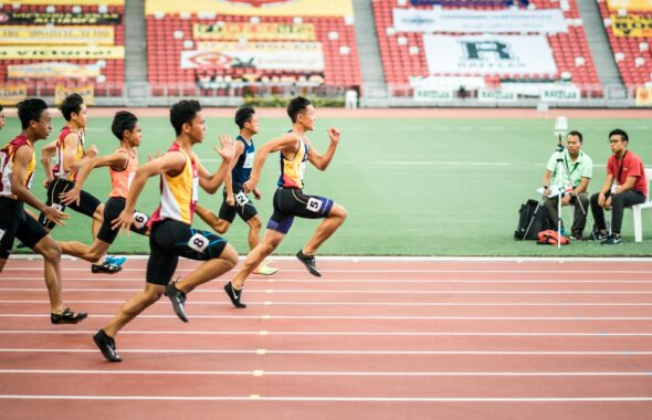 陸上競技場のトラックを走る選手たちを横から見た場面