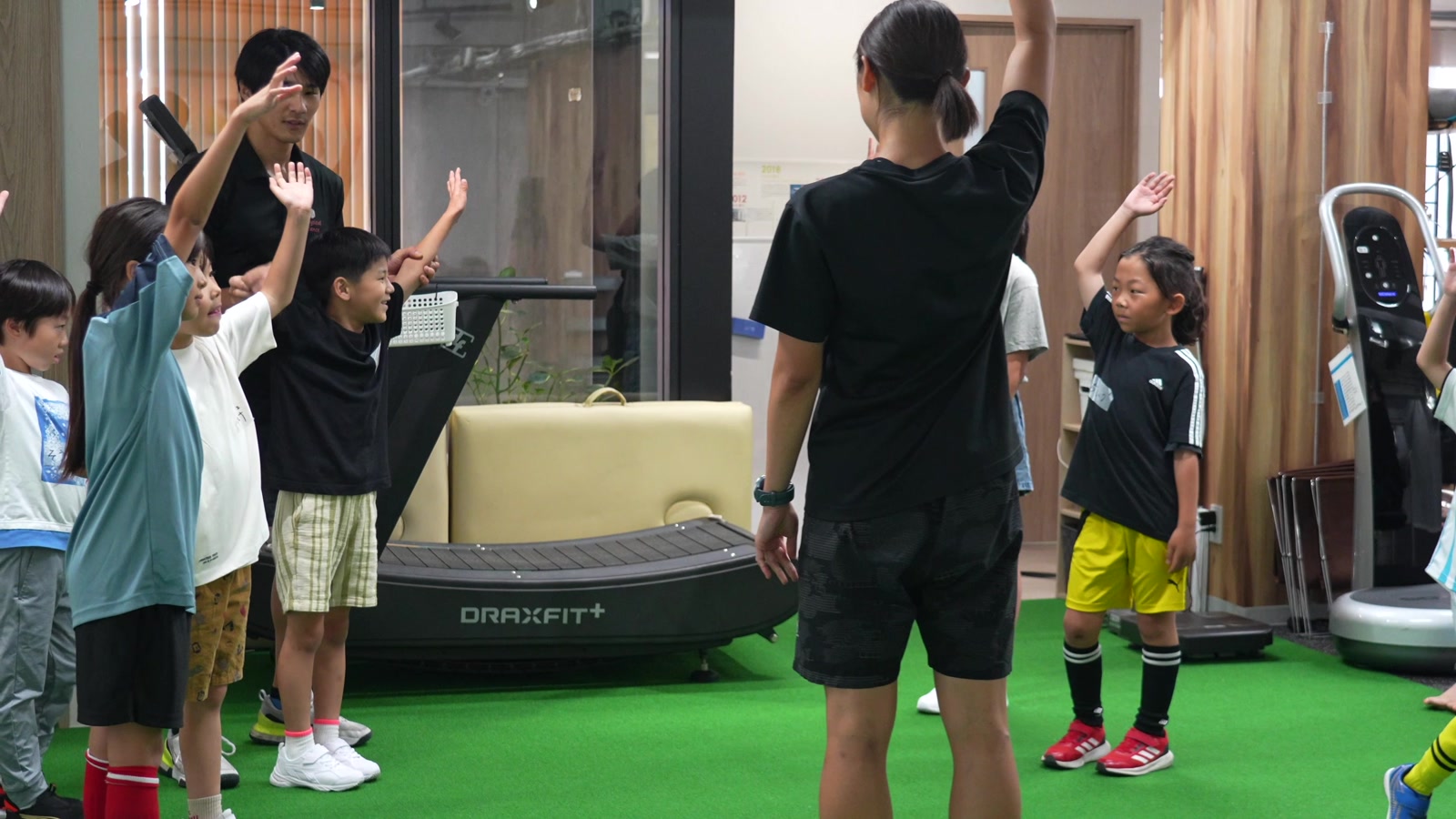 かけっこ教室でコーチの動きをまねて手を上げる子どもたち
