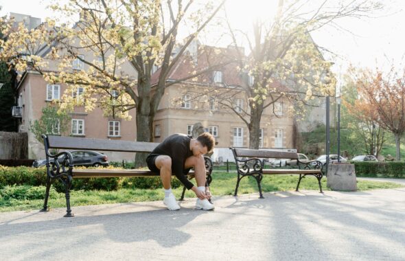 公園のベンチに座ってランニングシューズのひもを結ぶ人
